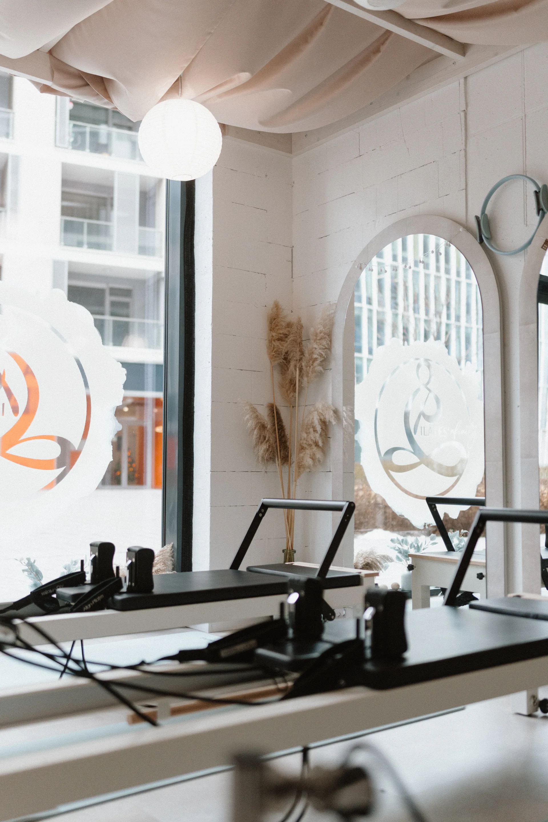 Pilates’nfinity budaparti reformer stúdió belső tere reformer gépekkel, nagy üvegablakokkal és a stúdió logójával.