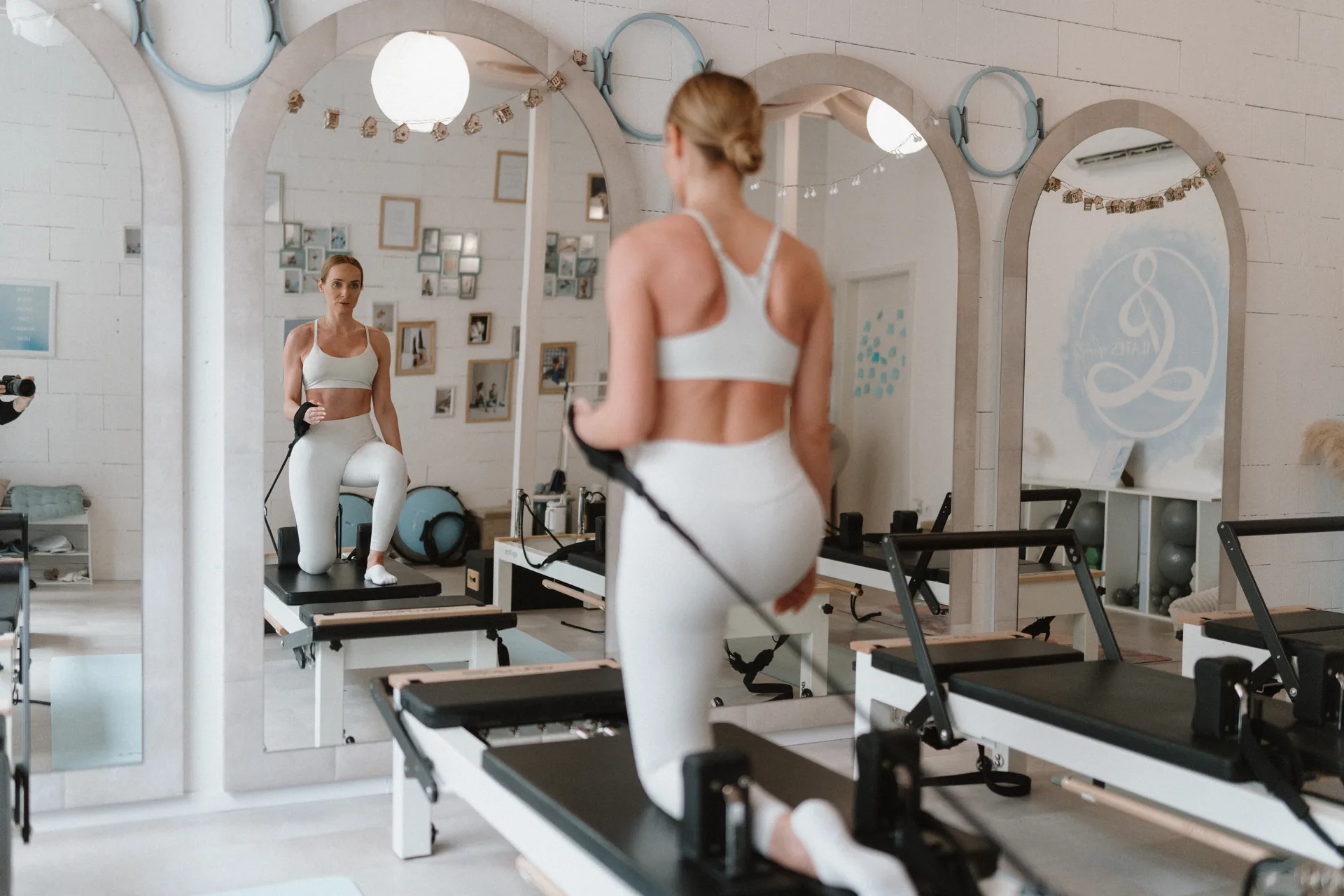 Oktató manuális korrekcióval segít lapocka kontrollt és vállövi stabilitást találni oldalplank reformer pilates gyakorlat közben a Pilates’nfinity stúdióban.