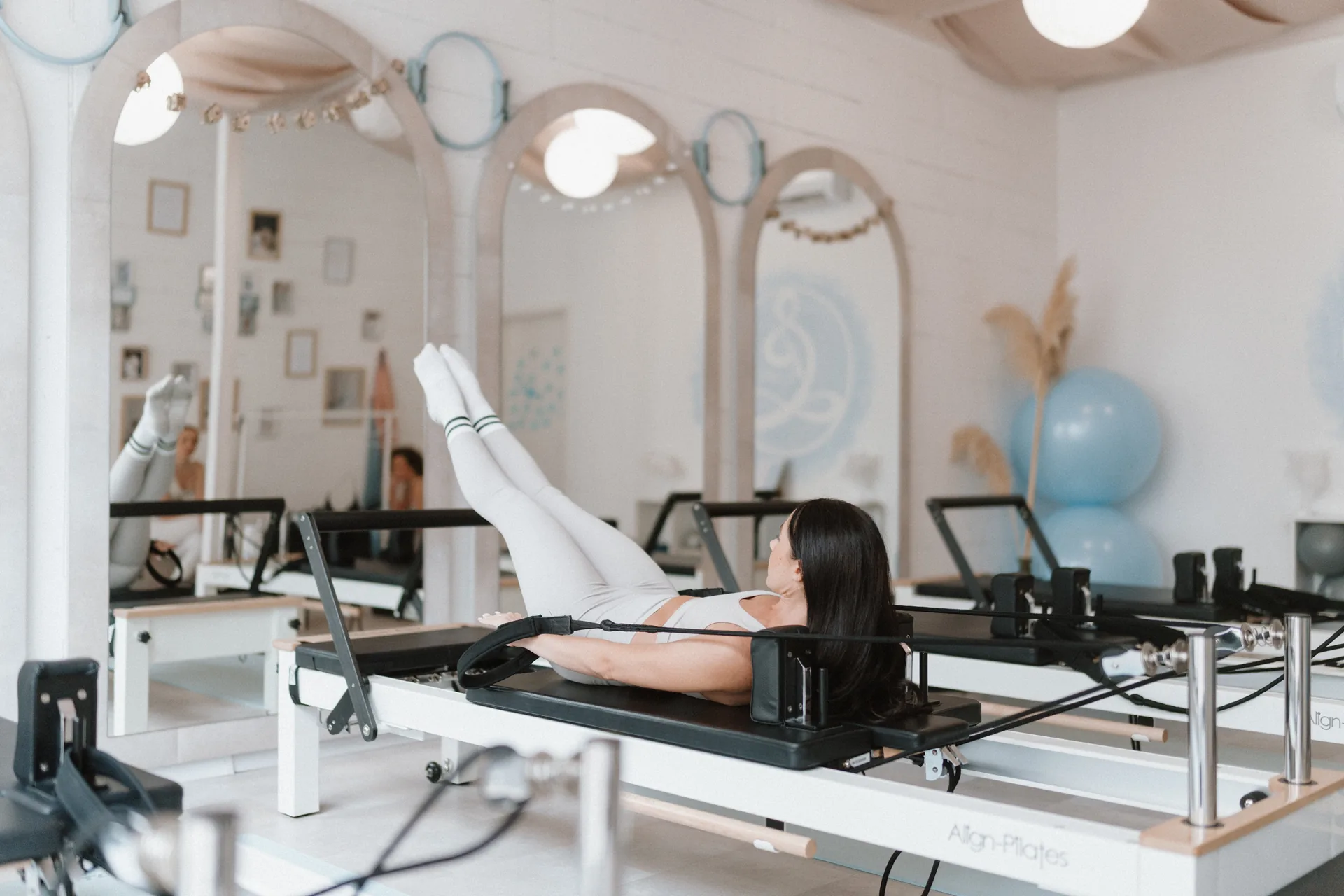 Reformer pilates óra a Pilates’nfinity stúdióban: vendég kontrollált törzstartással dolgozik a gépen, világos, letisztult térben.